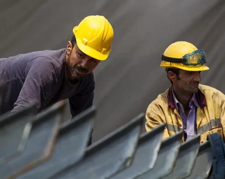 A photo of two male construction workers wearing yellow hard hats.