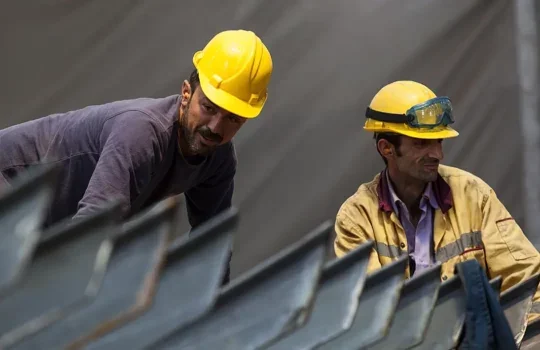 A photo of two male construction workers wearing yellow hard hats.