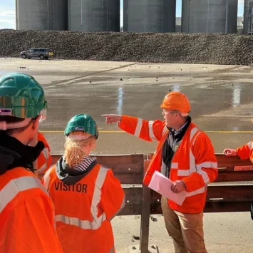 Group of people in high-vis jackets and hard hats being shown around the site of a sugar silo