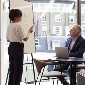 Male and female senior co-workers next to a whiteboard in an office