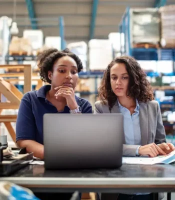 Two women in a factory looking at a laptop