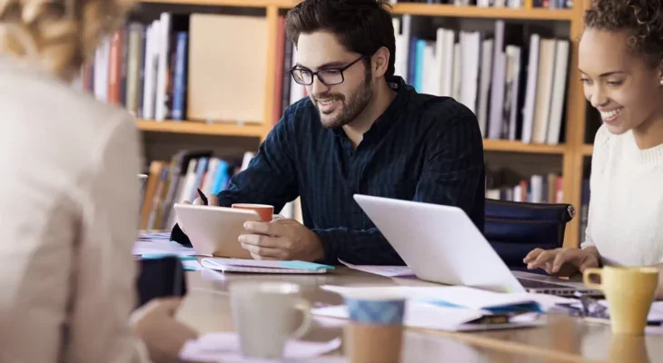 A group of people at a desk with laptops