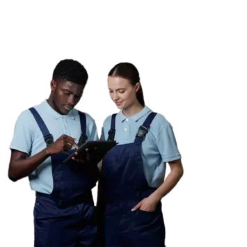 Two young workers in dungarees looking at a tablet, stood in a warehouse full of soft drinks