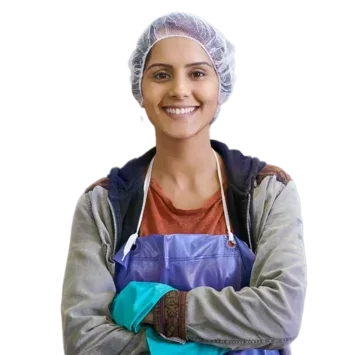 Female factory worker wearing a hairnet and apron, smiling at the camera