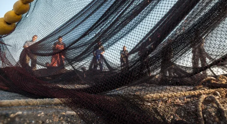 Commercial fishermen holding up a large fishing net